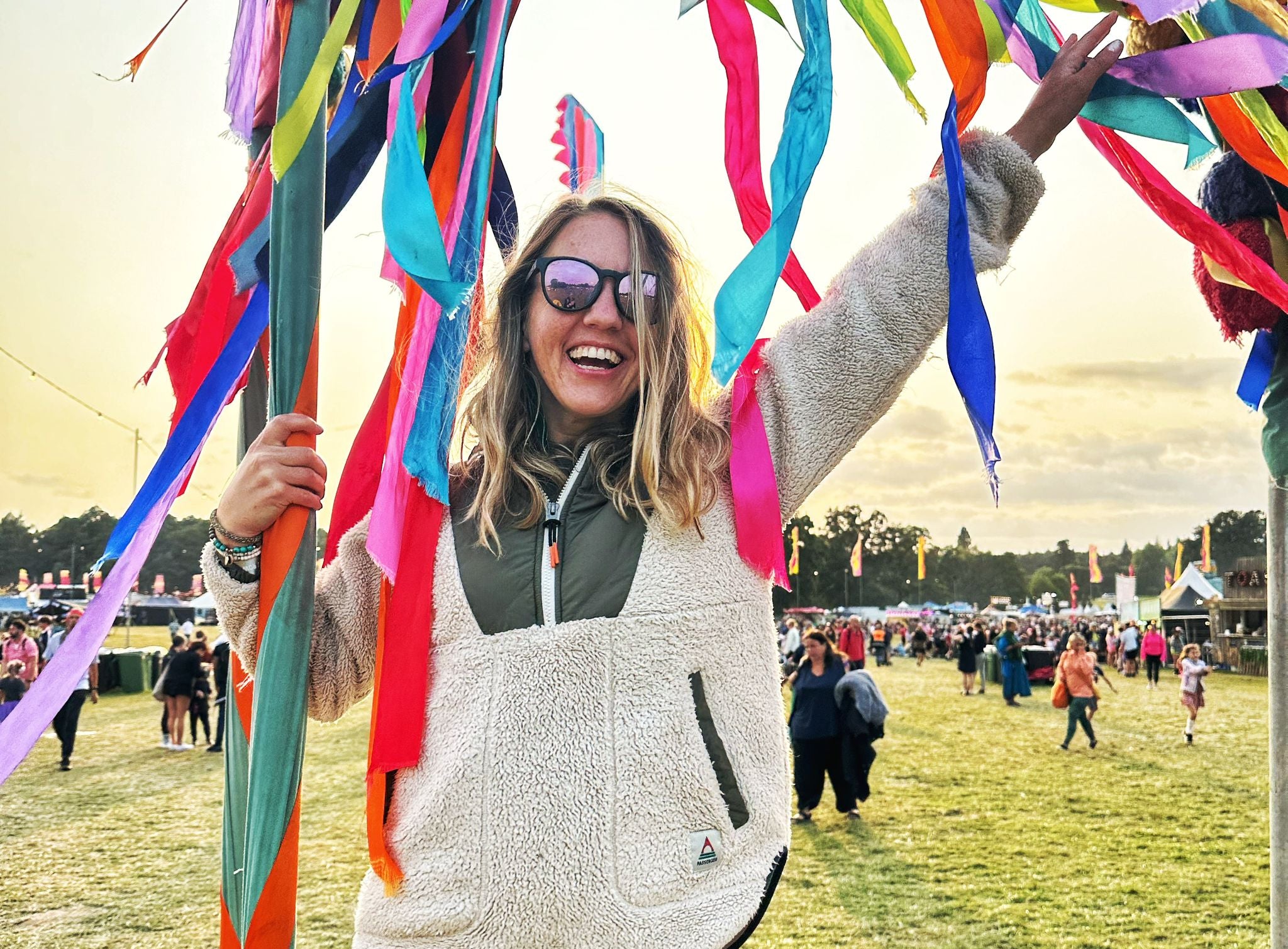 Person at a festival holding colorful ribbons with a crowd in the background