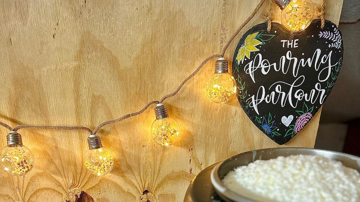 Black pot with white contents on a wooden surface with fairy lights and a decorative sign.